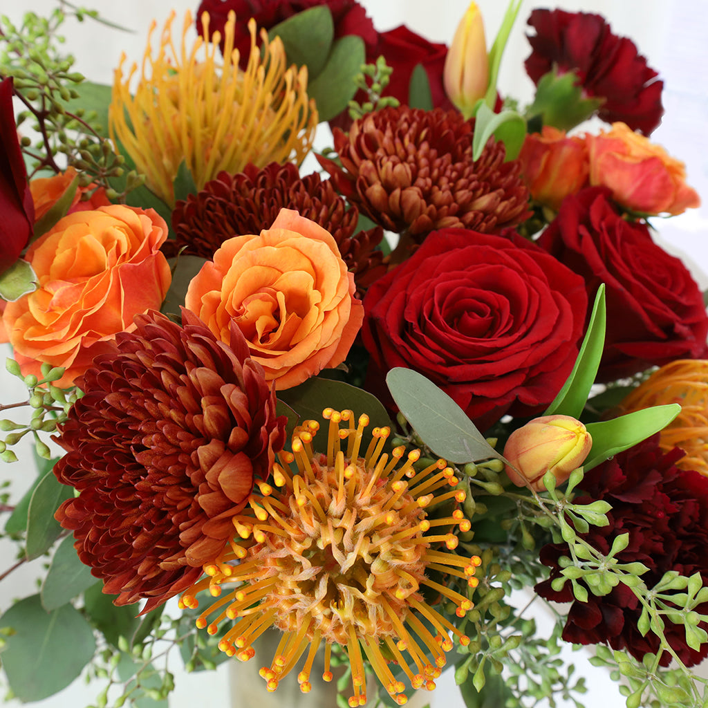Bouquet of Freedom Roses, Tulips, Orange Spray Roses, Spider Mums, and Pincushion Protea with Seeded Eucalyptus greeneries.