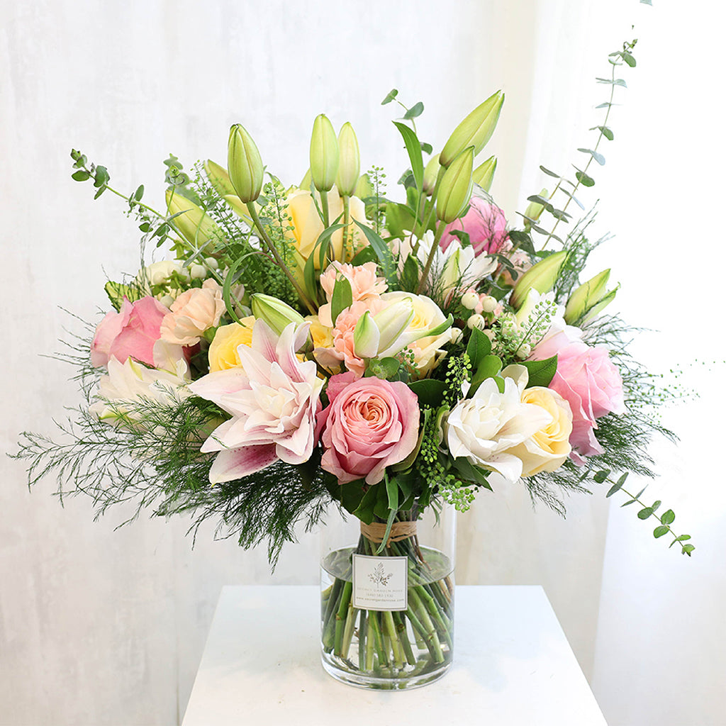 Bouquet of Oriental Lilies, Flamingo Roses, Creme De La Creme Roses, Hypericum, and Carnations with Eucalyptus, Lemon Leaves, Green Tree Fern, and Thlasip greeneries.
