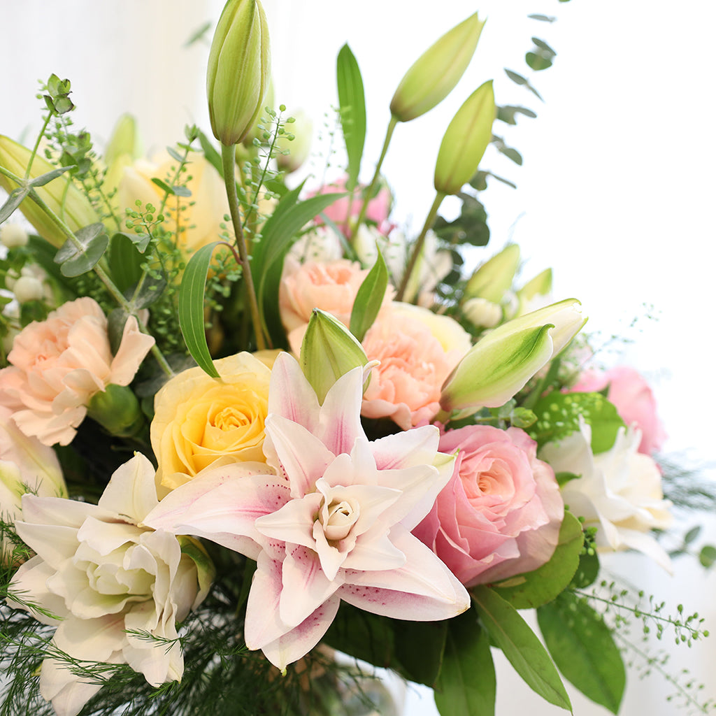 Bouquet of Oriental Lilies, Flamingo Roses, Creme De La Creme Roses, Hypericum, and Carnations with Eucalyptus, Lemon Leaves, Green Tree Fern, and Thlasip greeneries.
